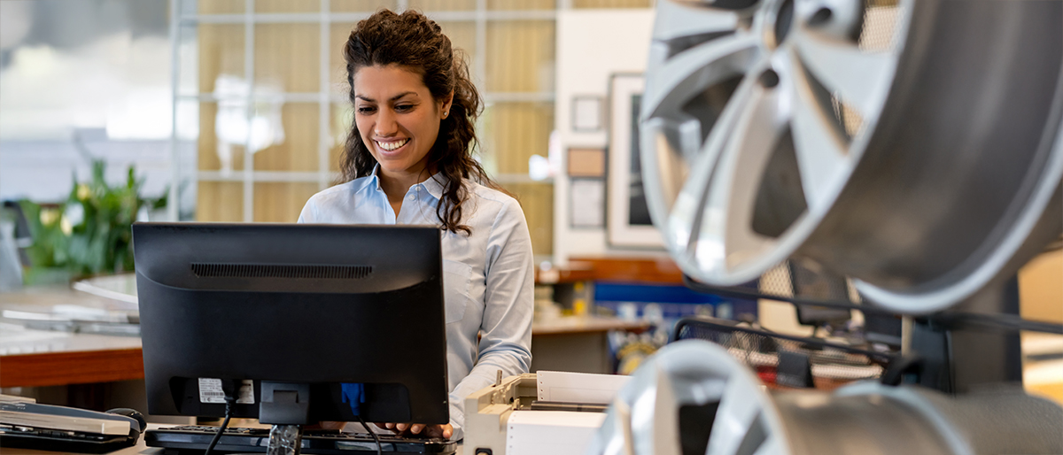 A woman using a computer in an auto parts dealership