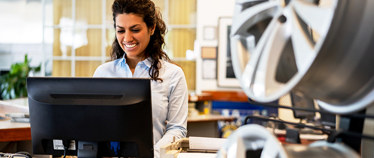 A woman using a computer in an auto parts dealership